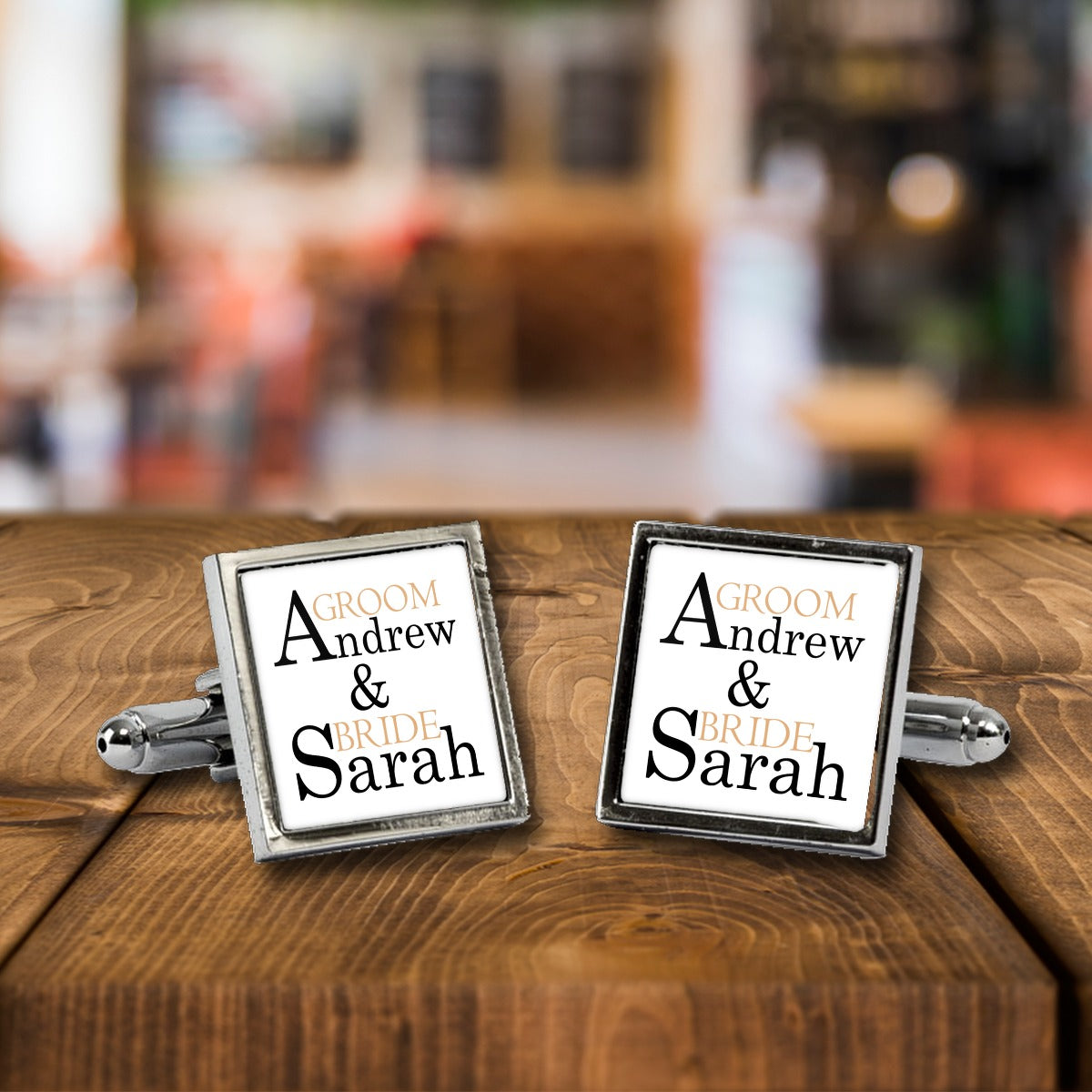 Personalised Groom & Bride Names Cufflinks – Wedding Gift for Him – White or Black Print, Chrome or Rose Gold – Personalised Groom & Bride Names cufflinks, a chrome square pair with white print on a wooden bar table
