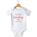 Flat mockup of the Our First Valentine's Day Daddy design on a short-sleeve baby vest