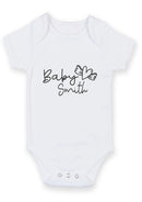 Flat mockup of the baby surname heart wings design on a short-sleeve baby vest