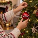 Child hanging a personalised name bauble on the Christmas tree