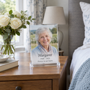 Memorial acrylic photo plaque on a bedside table beside white roses