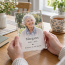 Memorial acrylic photo plaque held in hands at a kitchen table with a cup of tea