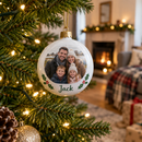 Personalised photo bauble hanging on a Christmas tree with warm fairy lights