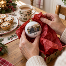 Grandmother unwrapping a personalised photo bauble at a festive kitchen table