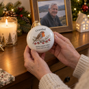 Memorial robin bauble held beside a candle and framed photo at Christmas