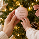 Mum and baby's hands touching a baby's first Christmas bauble on the tree