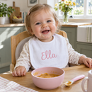 Baby wearing a personalised baby bib with the name Ella in a highchair at breakfast