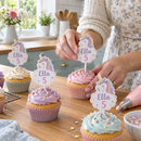 Personalised cupcake toppers being added to freshly iced cupcakes in a home kitchen