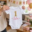 Personalised cake smash outfit with the name Isla held up at a first birthday party