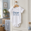 Personalised baby vest with the name Oscar hanging in a nursery