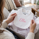 Personalised baby bib with the name Ella being unwrapped as a new baby gift