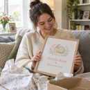 New mum unwrapping a personalised birth announcement print as a gift