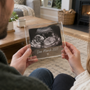 Couple holding a personalised pregnancy announcement plaque with scan photo