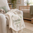 Personalised baby blanket with the name Freddie draped over a nursery chair