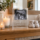 Personalised pregnancy announcement plaque on a mantelpiece with baby booties