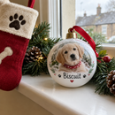 Personalised pet's first Christmas bauble on a windowsill beside a dog stocking