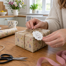 Tying a personalised gift tag onto a wrapped birthday present at the kitchen table