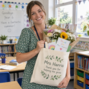 Teacher in a classroom holding a personalised tote bag filled with flowers