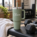 Personalised 40oz tumbler with handle with the name Olivia at the gym beside a towel