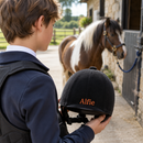 Riding hat with personalised helmet name decals reading Alfie at a stable yard