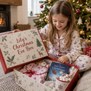 Child opening a personalised Christmas Eve box with the name Lily by the tree