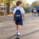 Boy carrying a personalised drawstring PE bag across the school playground