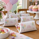 Personalised pillow treat boxes on a birthday party table with sweets