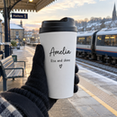 Personalised travel coffee cup with the name Amelia held at a train station on a cold morning