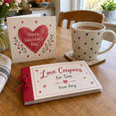 Personalised love coupon book on a kitchen table with a Valentine's card