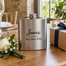 Personalised hip flask with the name James on a wedding table with a buttonhole