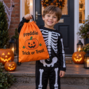 Boy in a skeleton costume holding a personalised trick or treat bag at a front door