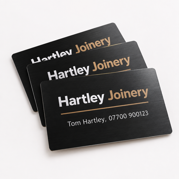 Metal business cards on a white background, showing an example personalised design