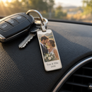 Personalised photo keyring: a personalised slim rectangle metal keyring with a couple's wedding photo and the text 'Tom & Ellie 2026' hanging from car keys on a car dashboard