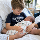 Boy in a personalised big brother t-shirt meeting his new baby sibling