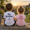 Siblings sitting together wearing personalised big brother and big sister t-shirts