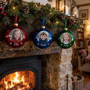 A row of personalised photo baubles in red, blue and green mirror finishes on a mantelpiece garland, each with a different child's photo and names 'Ella', 'Noah'