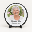 Personalised round photo slate printed with a photo of a smiling grandmother with the text Nanna Pat and Always in our hearts, on a plain background
