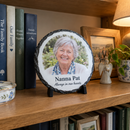 Personalised round photo slate, on a bookshelf among family books and trinkets