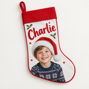 A personalised Christmas stocking with a white canvas body, a red border cuff and a red hanging loop, printed with a photo of a smiling little boy in a Santa hat