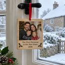 Personalised wooden Christmas decoration: a personalised rectangle wooden Christmas decoration with a family photo and the text 'Our First Christmas in Our New Home 2026' hanging from a red ribbon on a window