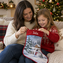 A mum and young daughter unwrapping a personalised Christmas stocking with a red border printed with the name 'Isla' and a snowy scene