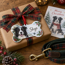 Personalised pet's first Christmas decoration: a personalised dog bone Christmas decoration printed with a border collie photo and the name 'Skye' on a wrapped present with a tartan ribbon next to a dog lead
