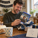 Man unwrapping a personalised video game case gift with his photo on the cover
