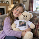 Personalised teddy bear: young girl hugging a cream teddy wearing a t-shirt printed with a grandad photo and 'Love you Grandad' in a cosy living room