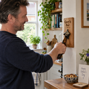Man using a personalised wall-mounted wooden bottle opener