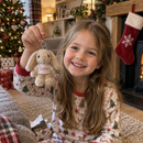Personalised mini bunny keyring: a little girl holding up a mini plush bunny keyring printed with the name 'Lottie' on Christmas morning beside a stocking, cosy British living room