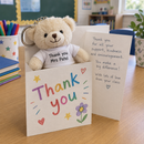 Personalised mini teddy bear keyring: a cream mini teddy bear keyring with a t-shirt printed 'Thank you Mrs Patel' tucked into a handmade thank-you card on a classroom table