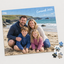 A completed A4 personalised photo jigsaw puzzle with visible cardboard piece cut lines, showing a family of four on a sandy British beach with the text 'Cornwall 2026'
