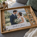 Personalised photo jigsaw: a personalised A4 photo jigsaw in progress showing a wedding photo with the text 'Sarah & James' on a wooden tray on a sofa, with scattered cardboard pieces