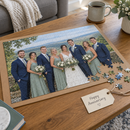 Personalised 300 piece jigsaw: a nearly finished personalised A3 photo jigsaw of a wedding party on a puzzle board with a gift tag reading 'Happy Anniversary' beside it on a coffee table